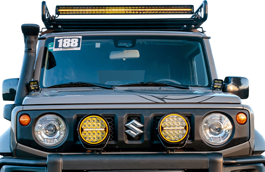 Front view of a Suzuki Jimny with LED accessories by Strands Lighting Division: 2x Night Ranger 7 inch spotlights and Siberia Lightbar curved 42 inch single row as working light on the roof