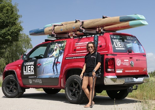 Brand ambassador Susanne Lier in front of her converted VW Amarok pickup with SUP equipment and SUP rack roof rack with 3 SUP boards on the roof