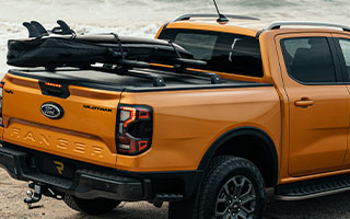 Mountain Top Evo Rollo mit Querträger und Surfbrett auf einem Ford Ranger am Strand