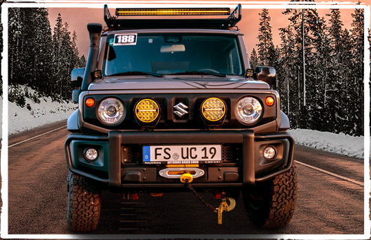 Suzuki Jimny conversion by Ullstein Concepts on a forest road. The winch bumper and tuning parts are sparkling in the sunset