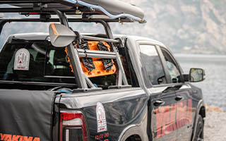 Schwarzer Pickup am Strand mit viel Offroadzubehör wie Druckwasserspeicher oder Paddelhalterung